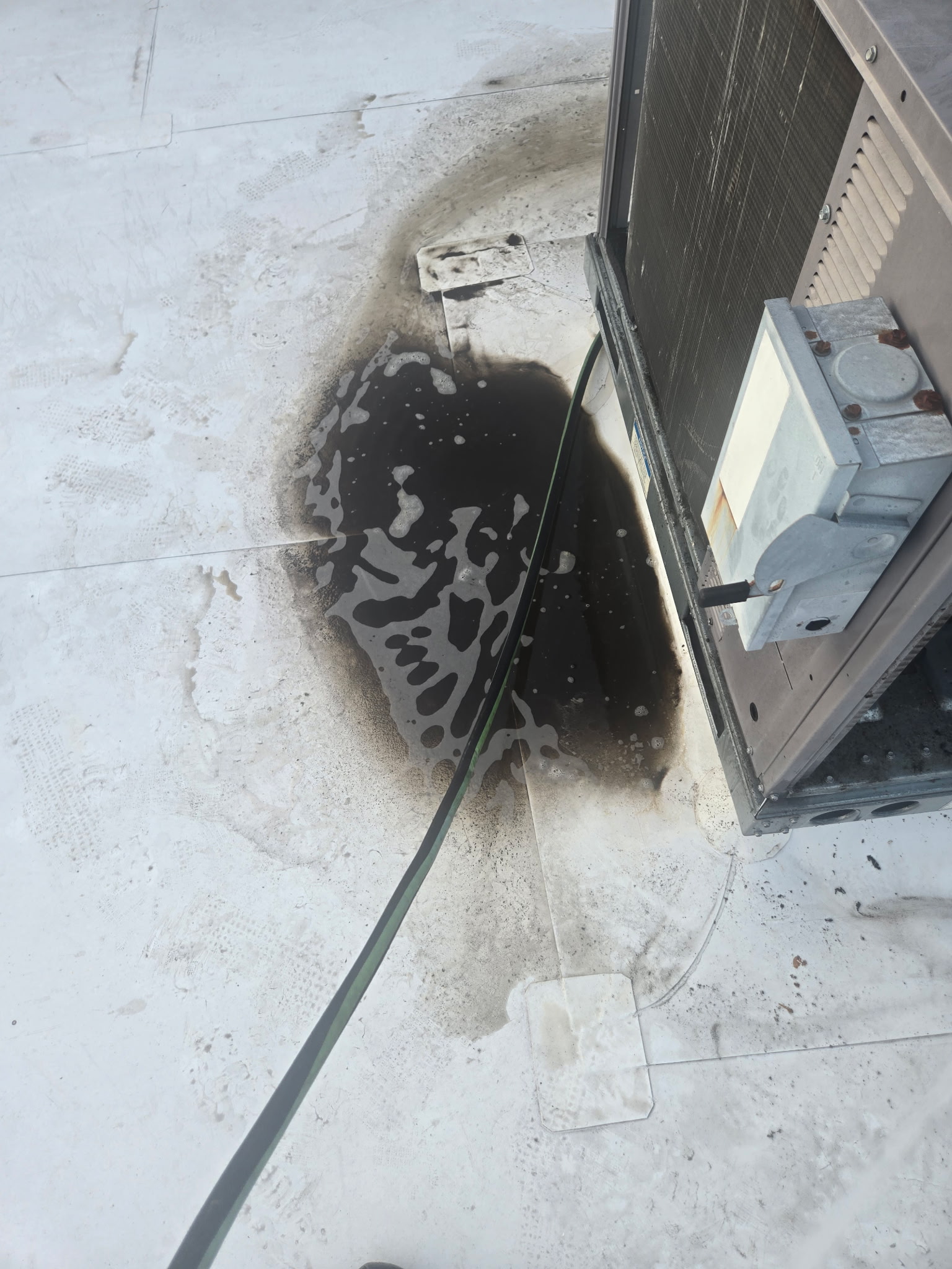 Rooftop HVAC unit with hose during coil cleaning